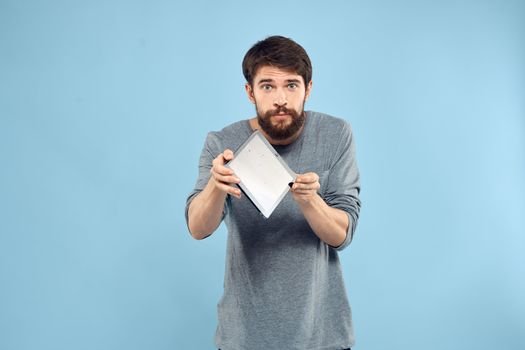 Emotional man with a tablet in the hands of a wireless device internet technology lifestyle blue background. High quality photo