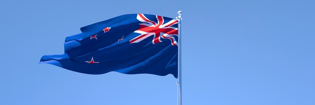 3D rendering of the national flag of New Zealand waving in the wind against a blue sky