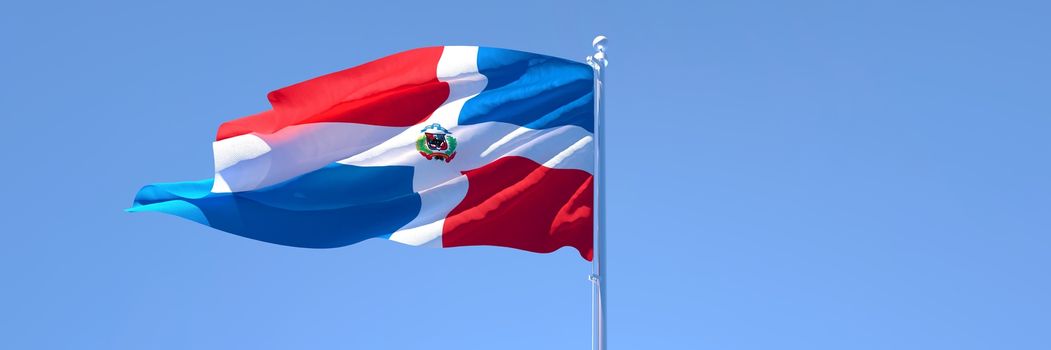 3D rendering of the national flag of Dominican Republic waving in the wind against a blue sky