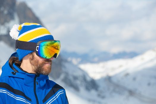 Close up portrait of man skier in hat and ski goggles mask looking at mountain range Col Gallina Cortina d'Ampezzo Dolomites