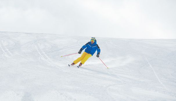 Alpine Skier skiing downhill on piste in high mountains front view