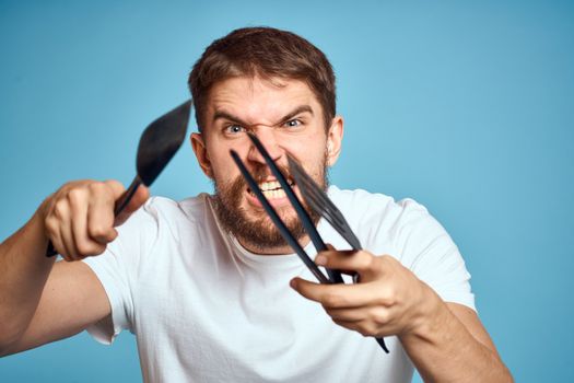 Bearded man with tools for cooking on a blue background and a white T-shirt shovel. High quality photo