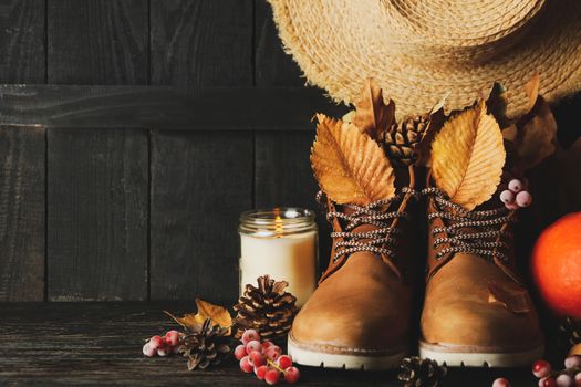 Concept of autumn wear with boots and leaves on wooden background