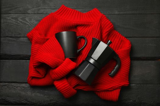 Red sweater with coffee maker and cup on wooden background