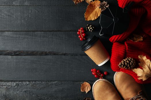 Autumn concept with sweater, coffee and boots on wooden table