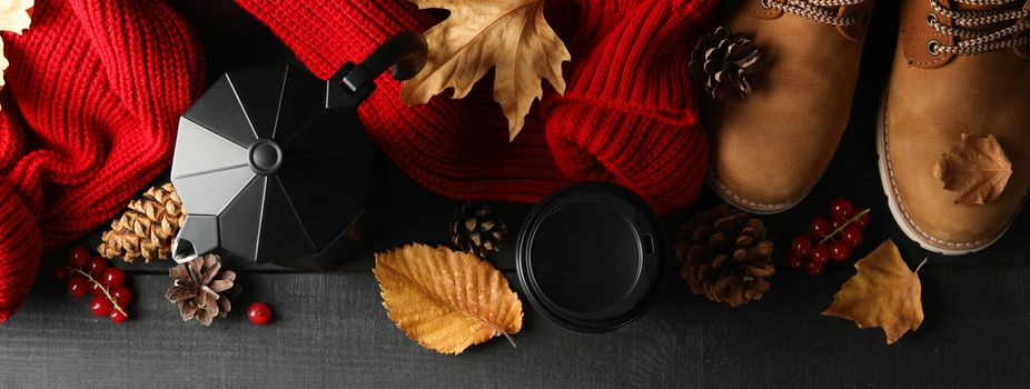 Autumn concept with sweater, coffee and boots on wooden table