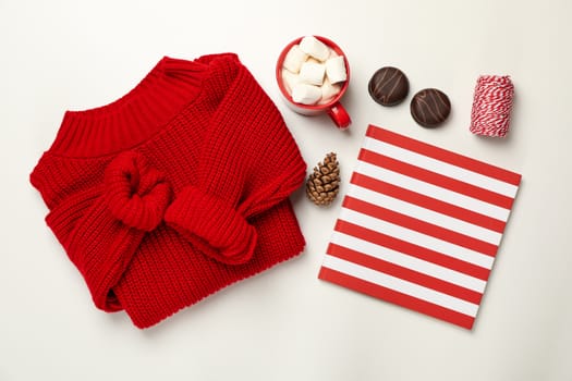 Sweater, cup of coffee with marshmallow, cone, copybook, biscuits and string on white background