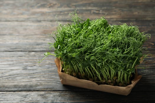 Green peas sprouts on wooden background, space for text