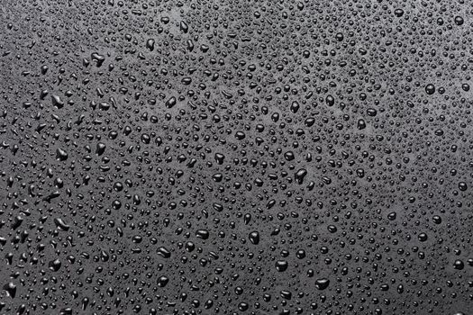 water drops on abstract flat black hydrophobic surface macro background.