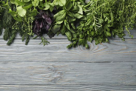 Different herbs on gray wooden background, top view