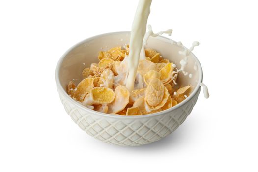 Milk is poured into a bowl with muesli, isolated on white background