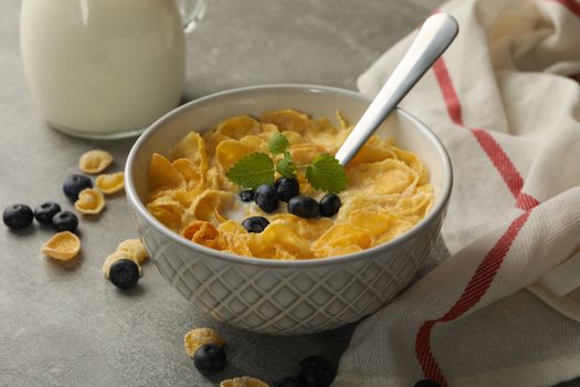 Concept of breakfast with muesli, milk and blueberry on gray table