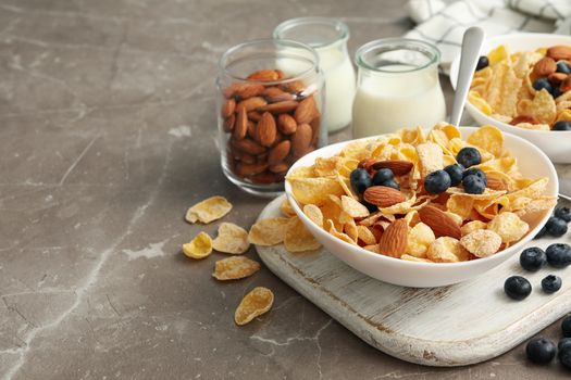 Concept of breakfast with muesli, berry, nut and milk on gray table