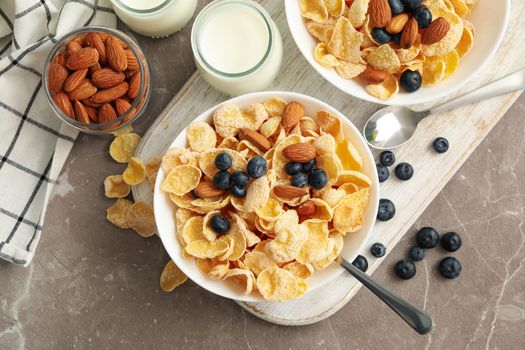 Concept of breakfast with muesli, berry, nut and milk on gray table