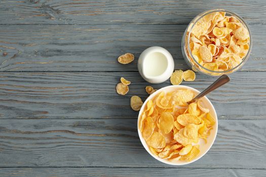 Milk, bowl and jar of muesli on wooden background