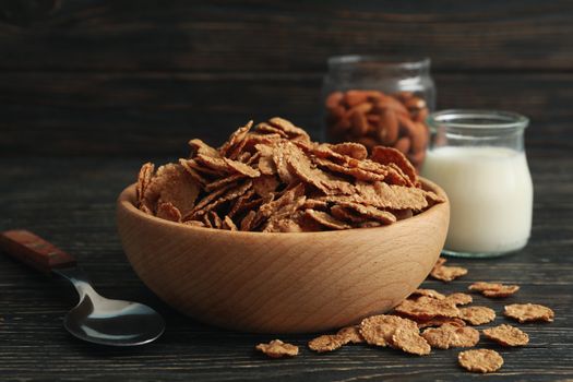 Muesli, milk, almond and spoon on wooden table