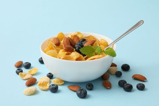 Bowl with muesli, almond, mint and blueberry on blue background