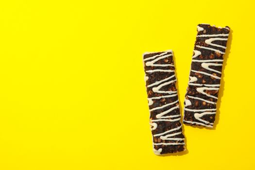 Tasty granola bars on yellow background, space for text