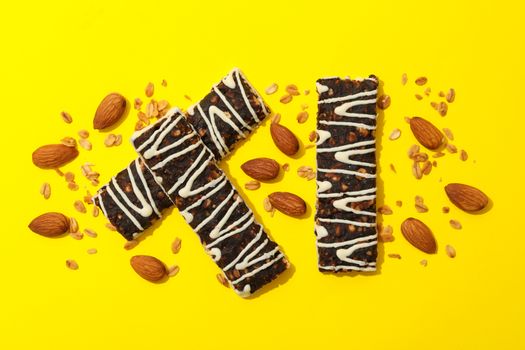 Tasty granola bars on yellow background, top view