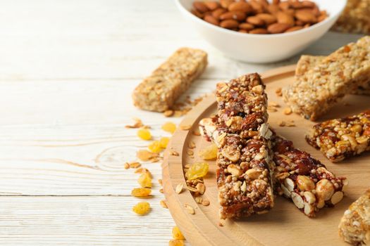 Tray with granola bars and bowl with almond on white wooden background