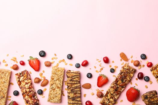 Tasty granola bars on pink background, top view