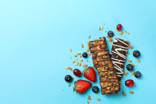 Tasty granola bars on blue background, top view