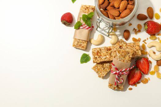 Granola bars, strawberry and nuts on white background, space for text