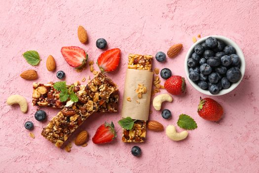 Granola bars and bowl with blueberry on pink background, top view