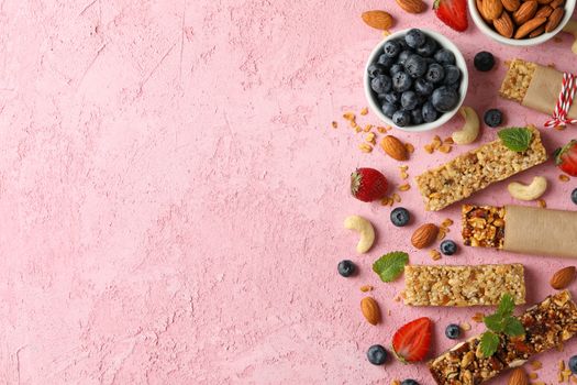 Granola bars and bowl with blueberry on pink background, top view