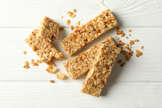 Tasty granola bars on white wooden background