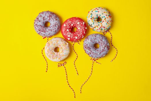 Concept of balloons made of donuts on yellow background