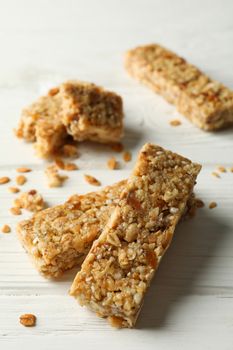 Tasty granola bars on white wooden background