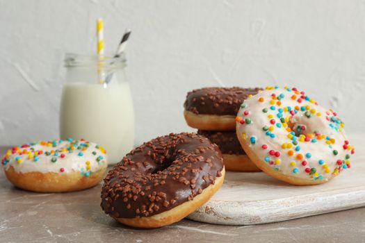 Jar of milk and tasty donuts on gray table