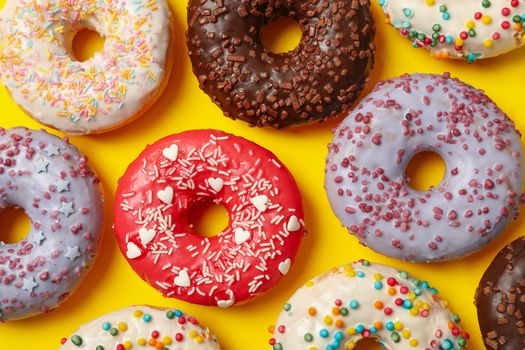 Flat lay with tasty donuts on yellow background