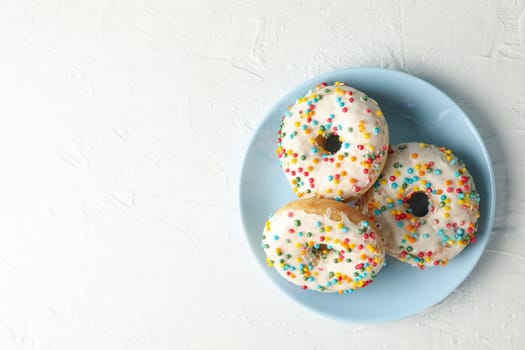 Plate with tasty donuts on white background