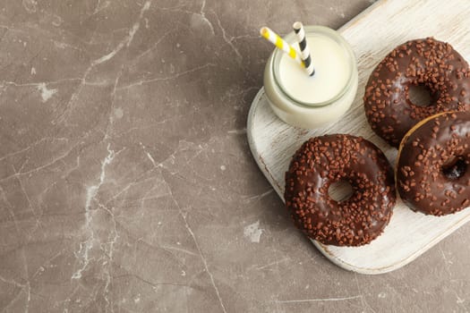 Jar of milk and tasty donuts on gray table