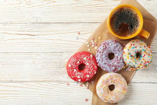 Coffee and tasty donuts on wooden background, top view