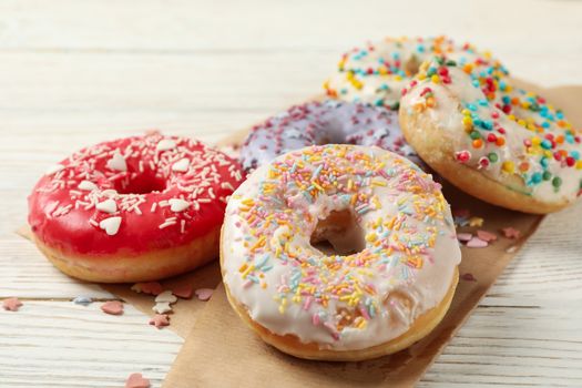 Baking paper with donuts on wooden background, close up