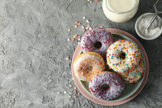 Concept of tasty food with donuts and milk on gray background