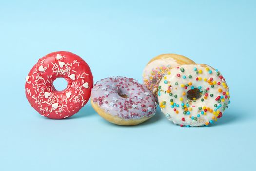 Four different tasty donuts on blue background