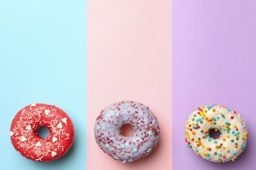 Tasty donuts on three tone background, top view