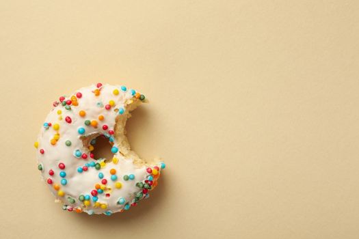 Tasty bitten donut on beige background, top view