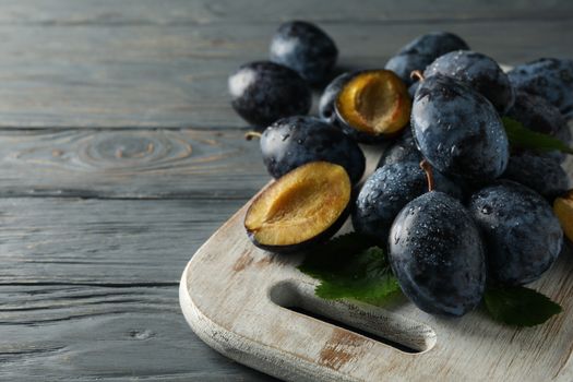 White board with fresh plums on wooden background