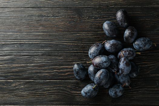 Fresh plums on wooden background, top view