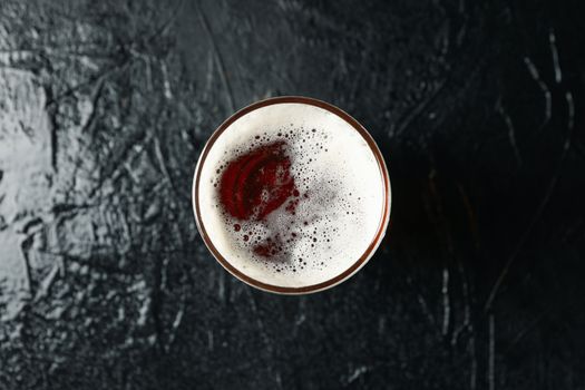 Glass of beer on black background, top view