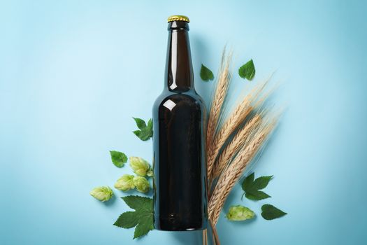 Bottle of beer, wheat and hop on blue background