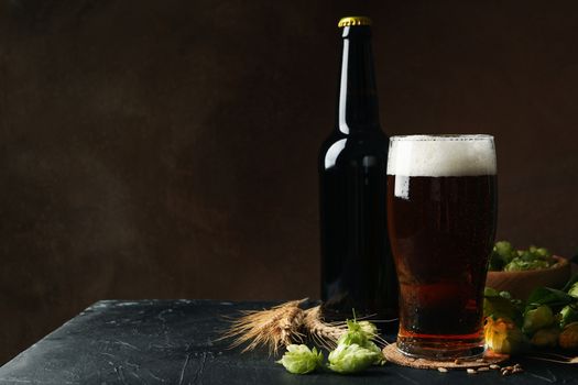 Beer, hop and wheat against brown background