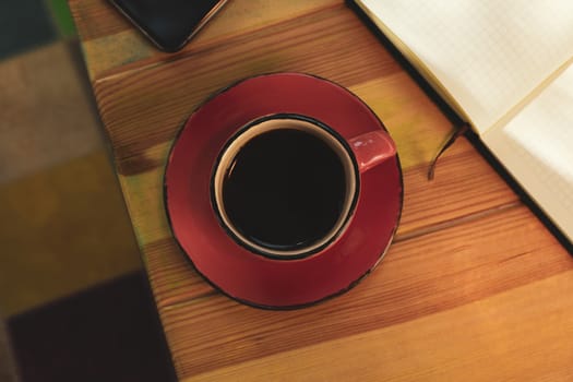 Cup of coffee, notebook and phone on wooden table