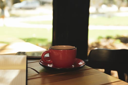 Cup of coffee, notebook and phone on wooden table