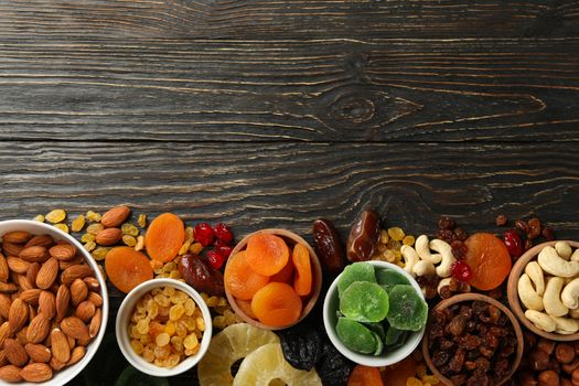 Bowls with dried fruits and nuts on wooden background